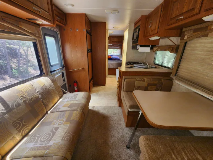 Spacious RV rental interior: kitchen, dinette, couch, and bedroom hallway visible. Ideal for comfortable travel.. Four Winds Chateau 2004