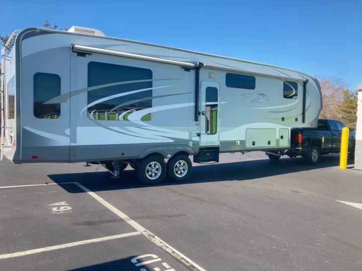 Large Open Range fifth-wheel RV rental, hitched to a pickup truck, parked in a lot on a clear day.. Open Range RV Open Range RV Fifth Wheel 2013