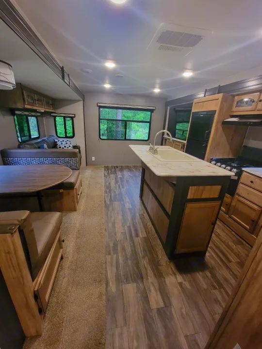 Bright RV rental interior with a modern kitchen, dining booth, and wood-look flooring.. Coachmen Freedom Express 323bhds 2019