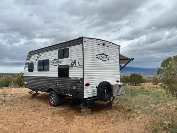 An Olympia Sport RV rental travel trailer camped in a vast, cloudy desert landscape. Perfect off-grid adventure.. Olympia Sport 2022