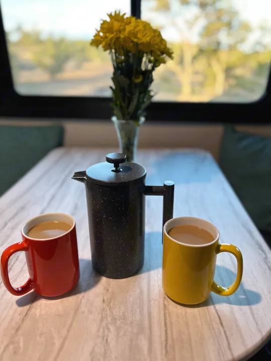 Enjoying a cozy coffee morning in an RV rental! A black French press, red and yellow mugs with coffee, and yellow flowers on the table.. Olympia Sport 2022