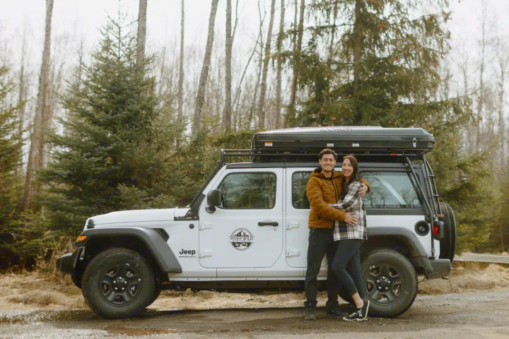 Happy couple with their River Wild Alaska Camper-Vans Jeep Wrangler RV rental and rooftop tent.. Jeep Wrangler 2023