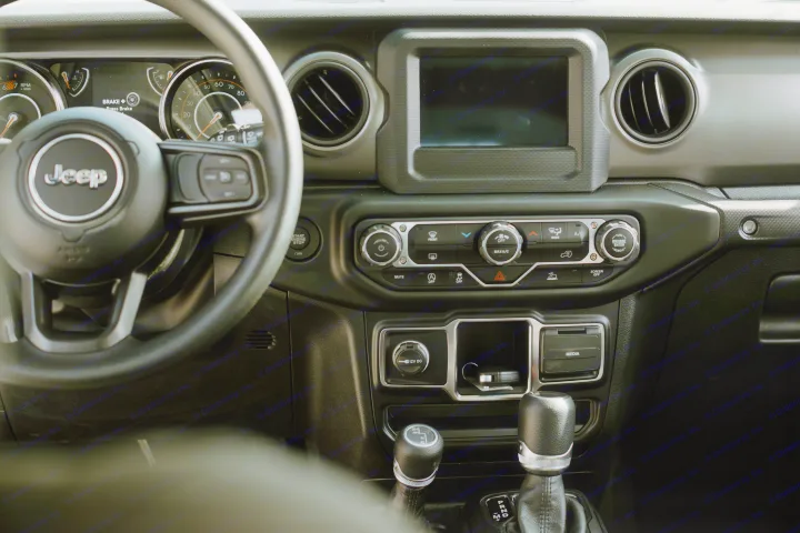 Jeep interior showing dashboard, steering wheel, screen, and shifters. Perfect for exploring, like a rugged rv rental adventure.. Jeep Wrangler 2023