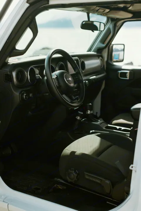 Bright Jeep interior: steering wheel, dashboard, front seat. Perfect for outdoor RV rental adventures.. Jeep Wrangler 2023