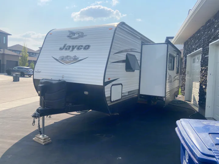 Jayco travel trailer with slide-out extended, parked on a residential driveway, suggesting an RV rental.. Jayco Jay Flight SLX 2018