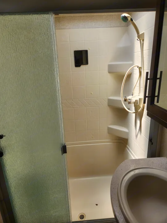 Inside an RV rental: compact shower stall with textured glass door, flexible shower head, and controls.. Keystone RV Cougar 2019