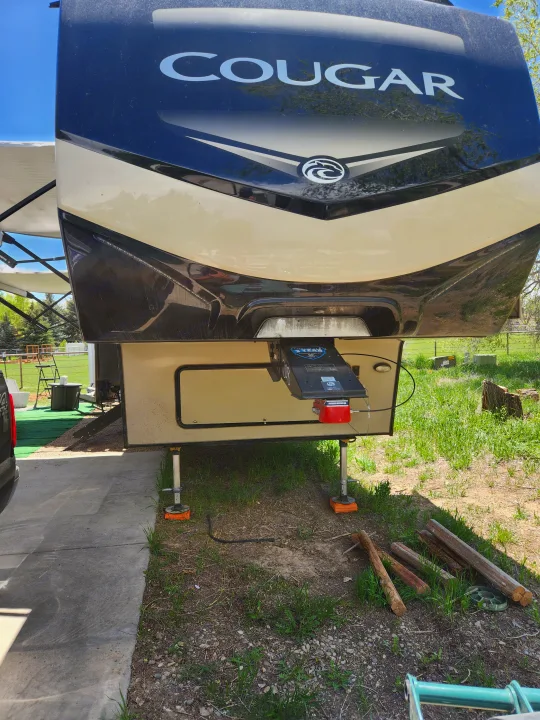 Cougar fifth-wheel RV rental, parked with leveling jacks on a concrete pad, ready for outdoor adventure.. Keystone RV Cougar 2019