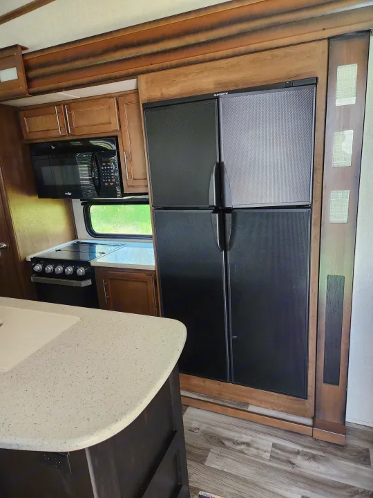 RV rental kitchen: Features a large Dometic fridge/freezer, microwave, and range in a spacious RV interior.. Keystone RV Cougar 2019