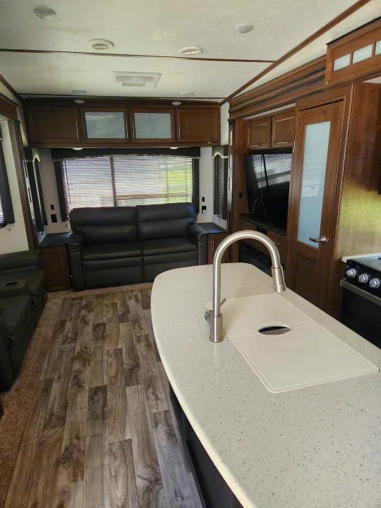 Modern RV rental interior features a sleek kitchen, comfy recliners, entertainment, and wood flooring.. Keystone RV Cougar 2019