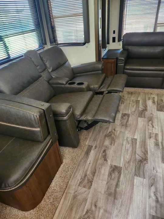 Comfortable RV rental living space with reclining theater seats, cupholders, wood-look floor, & window blinds.. Keystone RV Cougar 2019