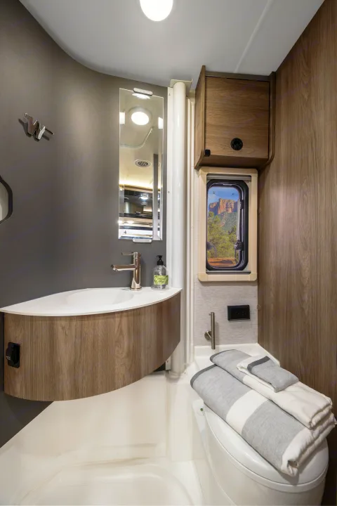 Winnebago RV rental bathroom: compact, modern design with sink, toilet, and scenic window views for comfortable travel.. Winnebago EKKO POP TOP 2027