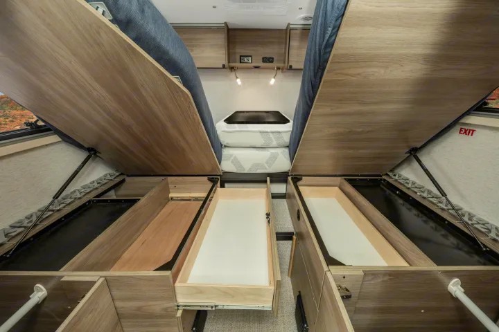 RV rental interior: beds lifted to reveal ample under-bed storage with multiple pull-out drawers, designed for efficient compact living.. Winnebago EKKO POP TOP 2027