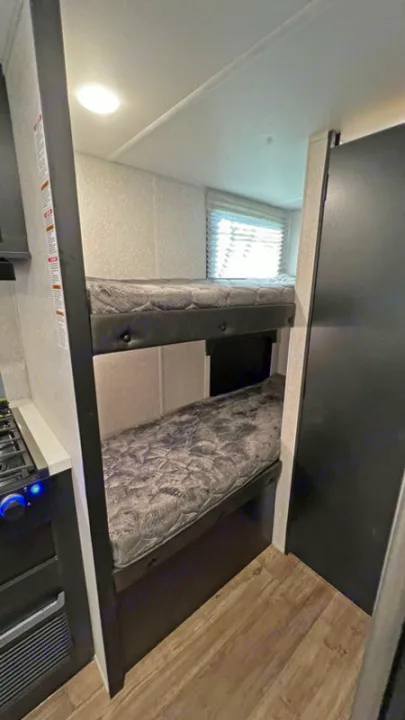 RV rental interior features bunk beds, a compact kitchen area, and a window.. Forest River Cherokee Wolf Pup Black Label 2022