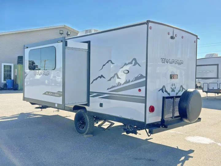 This modern Wolf Pup travel trailer, an ideal RV rental option, features a slide-out living area & rear spare tire.. Forest River Cherokee Wolf Pup Black Label 2022