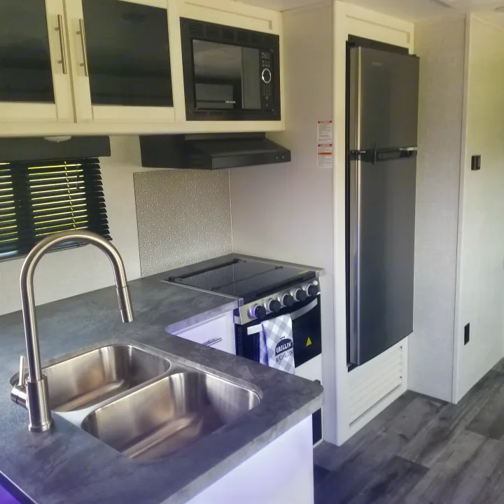 Compact RV rental kitchen: full-size fridge, stovetop, microwave, and double sink. Modern interior for comfortable adventures.. Crossroads RV Volante 2022