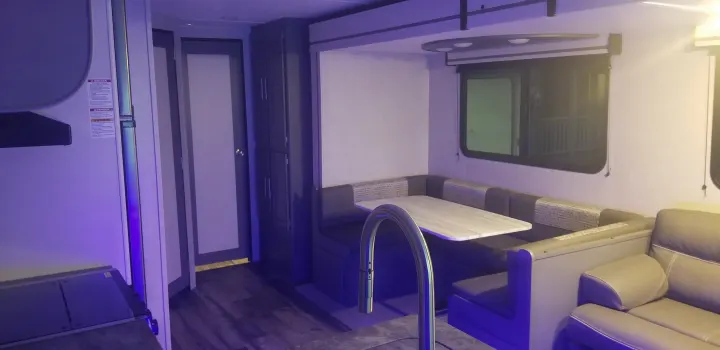 RV rental interior: A cozy dinette, sofa, and storage create a comfortable living space with blue ambient lighting.. Crossroads RV Volante 2022