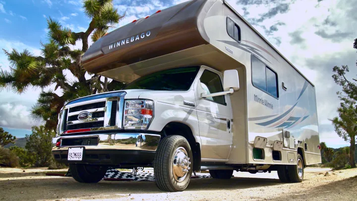 Winnebago Minnie Winnie Class C RV rental parked on a desert dirt road with Joshua trees. Ideal for outdoor adventures.. Winnebago Minnie Winnie 2017