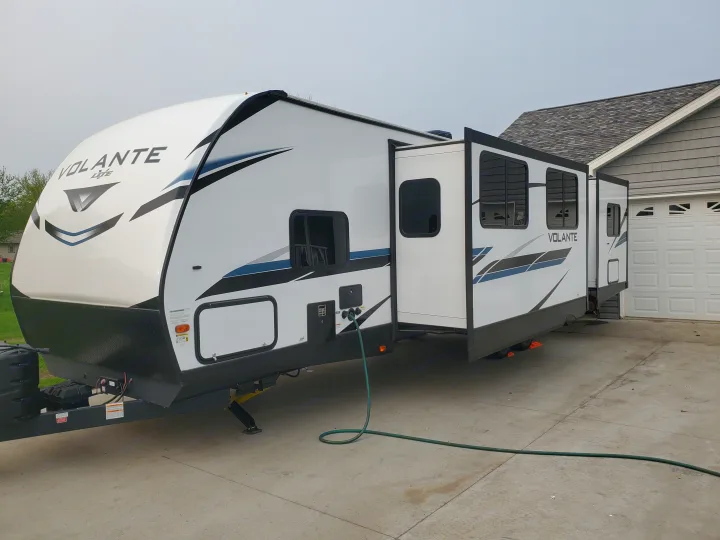 White Volante Lite RV travel trailer, ideal for an rv rental, parked with slide-outs extended on a driveway.. Crossroads RV Volante 2022