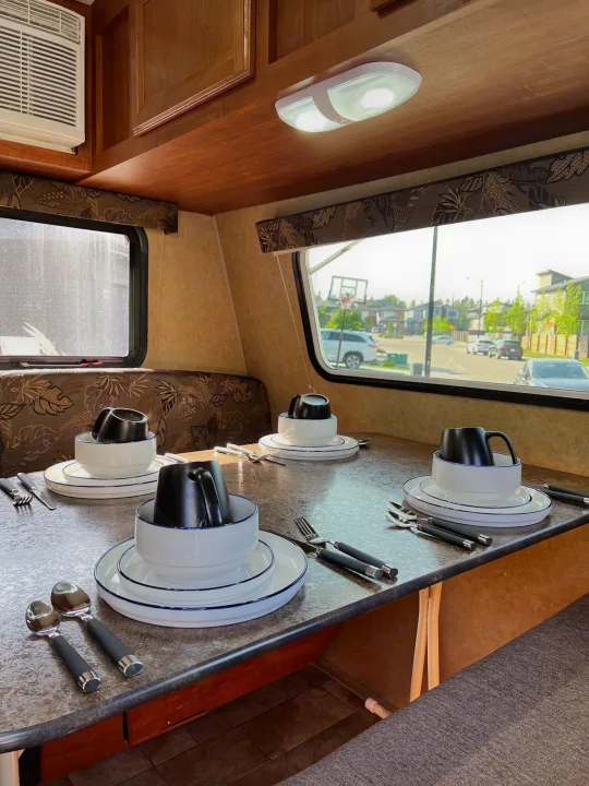 Cozy RV rental dining area set for four, with plates, mugs, and cutlery ready for a meal on the go.. Jayco Jay Flight Swift 154 BH Slx 2013