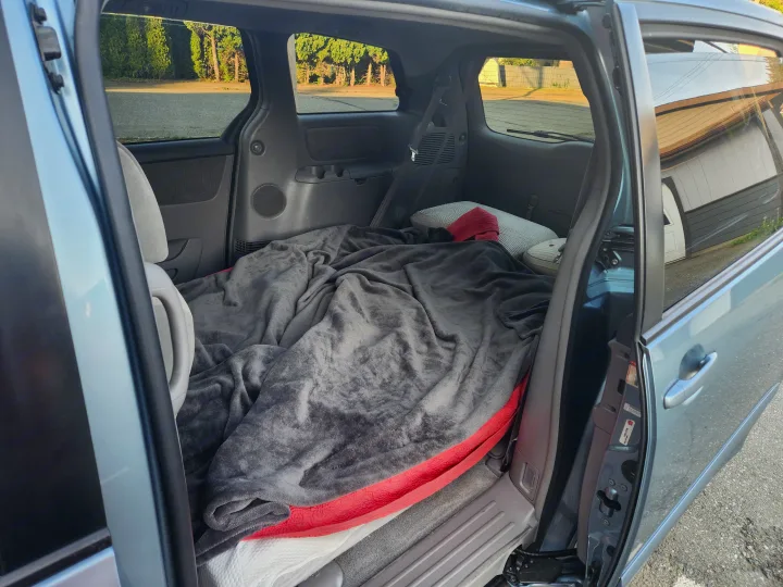 Minivan interior converted into a cozy sleeping space for travel, a clever alternative to an RV rental.. Toyota Sienna 2008