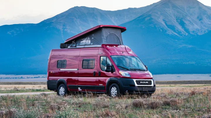 Red Winnebago Solis rv rental parked in a scenic mountain landscape, perfect for your next outdoor adventure.. Winnebago Solis PX 2023