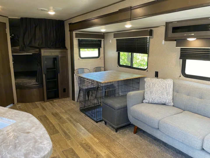 Enjoy this cozy RV rental interior with bunk beds, a dog crate integrated into the dining area, and a comfortable living space.. Jayco Jay Flight SLX 2021