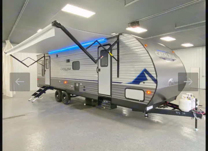 A modern grey Catalina travel trailer with an extended awning and blue lights, showcasing features for a comfortable rv rental experience.. Coachmen Catalina 2023