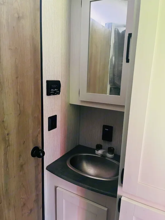 Compact RV rental bathroom featuring a sink, mirrored medicine cabinet, and climate controls.. Palomino PUMA 22RBC 2022