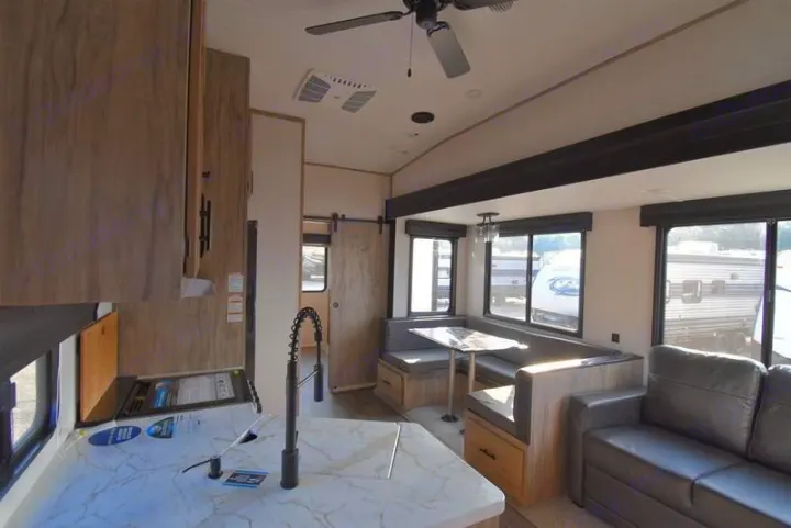 Spacious RV rental interior featuring a modern kitchen, comfortable dining booth, and living area.. Forest River Cherokee Arctic Wolf 2022