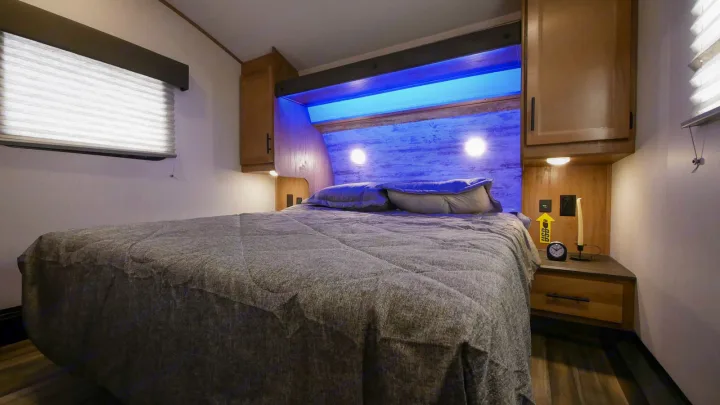 This inviting **rv rental** bedroom boasts a large bed, serene blue LED lighting, and convenient bedside power options.. Forest River Cherokee Arctic Wolf 2022