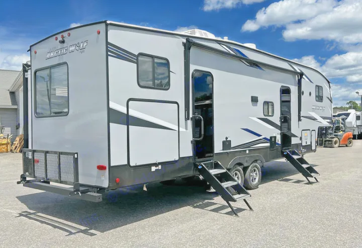 Grey Arctic Wolf RV travel trailer with multiple steps, an awning, and a rear cargo rack, suitable for rv rental.. Forest River Cherokee Arctic Wolf 2022
