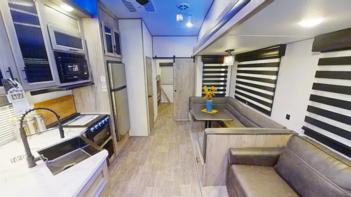 Spacious RV rental interior featuring a modern kitchen, dining booth, and comfortable living area.. Forest River Cherokee Arctic Wolf 2022
