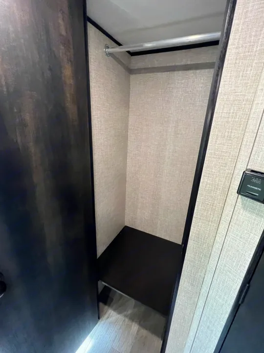 Empty RV rental closet, light textured walls, with a hanging rod & dark shelf for travel storage.. Jayco Jay Flight SLX 2022