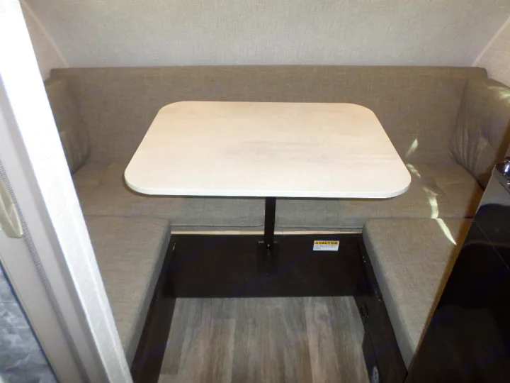 An RV rental's gray dinette booth and white table, offering a comfortable space for dining and activities.. Braxton Creek Bushwhacker Plus 2022