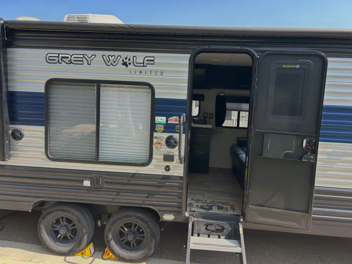 This Grey Wolf travel trailer RV rental is shown with its door open, revealing the interior and entrance steps.. Forest River Cherokee Grey Wolf Special Edition 2022