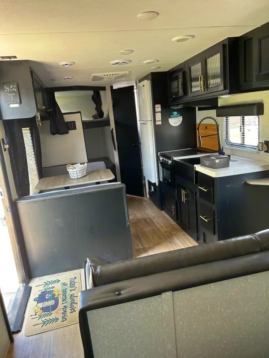 Spacious RV rental interior featuring a modern black kitchen, comfortable dining area, and bunk beds.. Forest River Cherokee Grey Wolf Special Edition 2022
