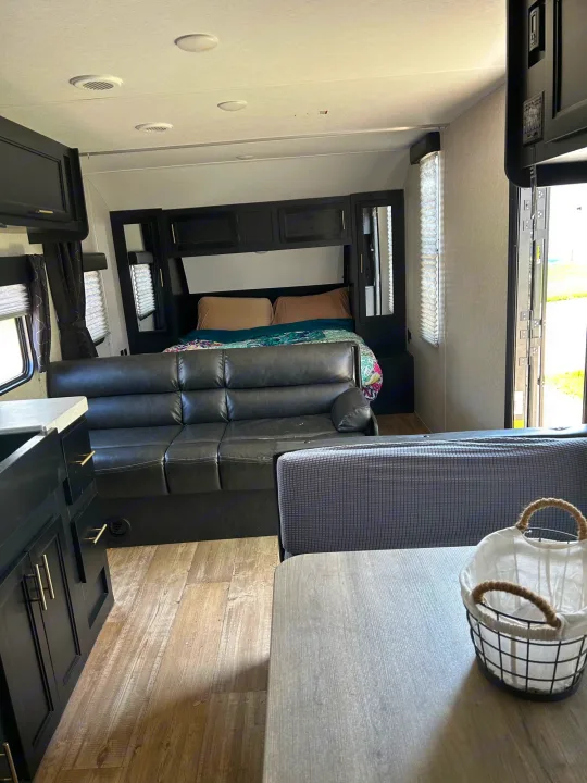 Cozy RV rental interior with a dark sofa, rear bed, and dining area. Your comfortable home on wheels.. Forest River Cherokee Grey Wolf Special Edition 2022