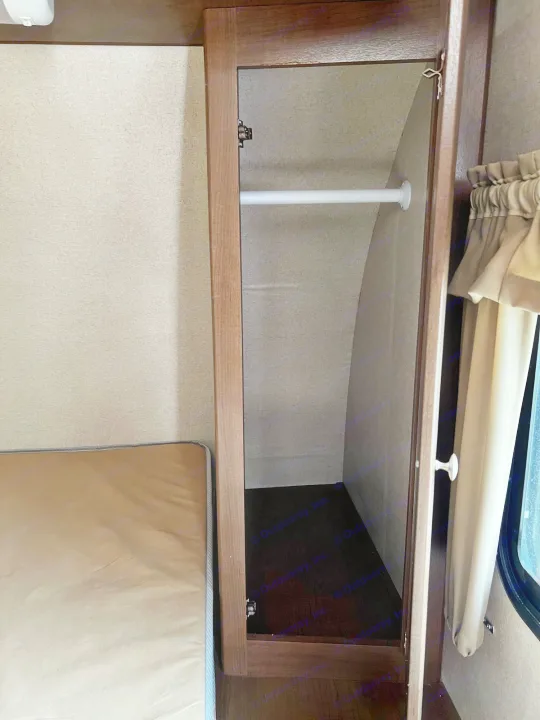 RV rental interior: A compact closet with a hanging rod, adjacent to a bed and window with curtains.. Shasta Oasis 2016