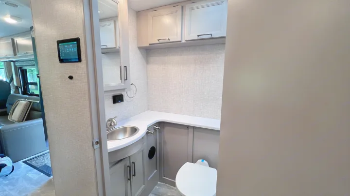 Compact RV rental bathroom showcasing a modern vanity, sink, toilet, and smart control panel in a stylish interior.. Thor Windsport 2023