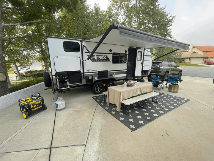 Camping table and benches with outdoor rug setup. Coachmen Apex Nano 2021