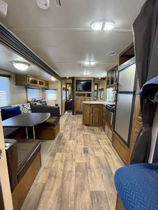 Spacious, modern RV rental interior with a full kitchen, cozy dinette, sofa, and light wood-look flooring.. Forest River Wildwood 2016