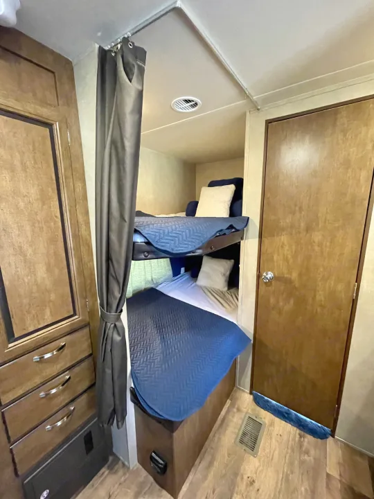 RV rental: View of stacked bunk beds with privacy curtain, adjacent wardrobe, and door. A cozy sleeping area for your travels.. Forest River Wildwood 2016