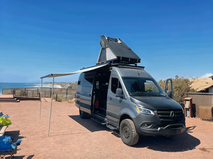 Custom RV rental: A Sprinter van with a rooftop tent and awning, perfectly set up for oceanfront camping.. Mercedes-Benz Sprinter 2020