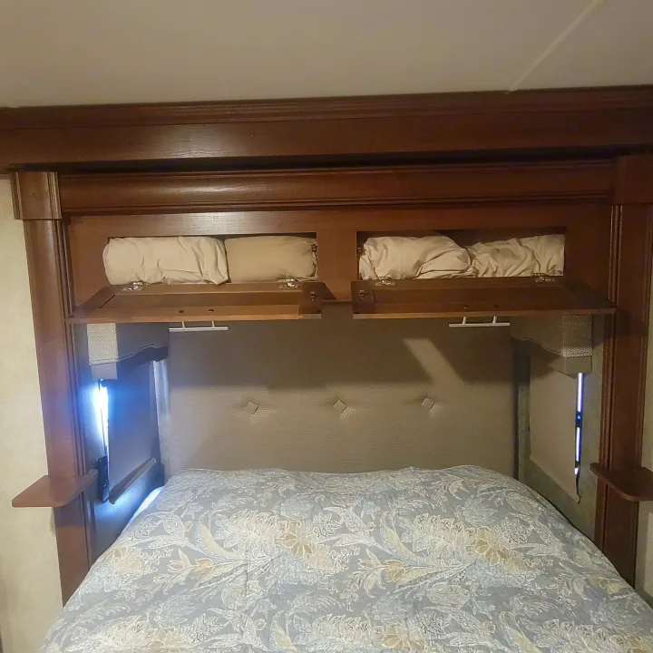 Cozy RV rental bedroom featuring practical overhead storage, a padded headboard, and comfortable, patterned bedding.. Georgetown GT5 2017