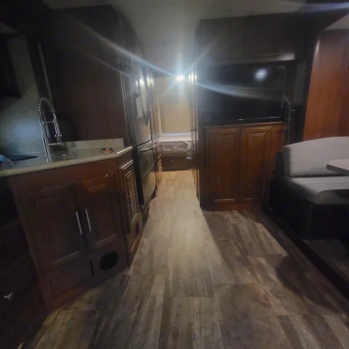 RV rental interior: A full view of the kitchen and living area, featuring dark wood cabinetry, a large sofa, and wood-look flooring.. Georgetown GT5 2017