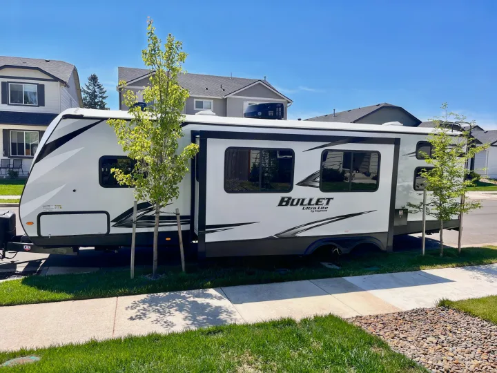 White Keystone Bullet travel trailer, ideal for an rv rental, parked on a sunny residential street.. Keystone Bullet 2021