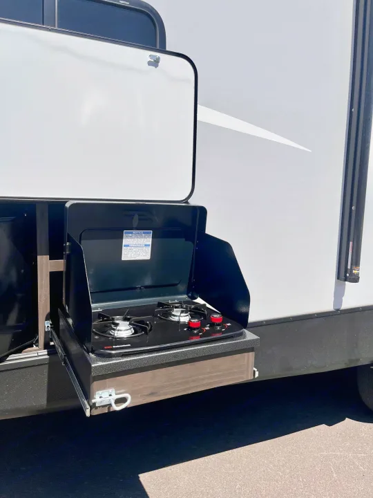 RV rental featuring a black, pull-out outdoor kitchen with a two-burner cooktop. Perfect for camping meals.. Keystone Bullet 2021