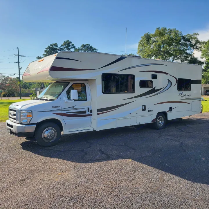 A white Coachmen Freelander Class C RV is parked on a sunlit asphalt driveway. Perfect for your next rv rental adventure!. Forest River Coachmen Freelander 2016
