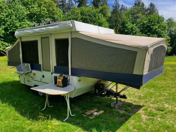 Pop-up camper with outdoor kitchen & power station set up in a sunny grassy field. Perfect for an RV rental.. Jayco Qwest 2003
