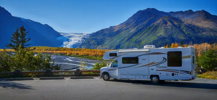 RV rental parked at scenic glacier viewpoint. White motorhome with mountains, river, and autumn foliage.. Forest River Coachmen Freelander 2014